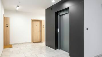 A hallway with two wooden doors, one with the number 45 and the other with 46, leading to an elevator.