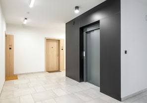 Een gang met twee houten deuren, waarvan één genummerd 45 en de andere 46, die naar een lift leiden.