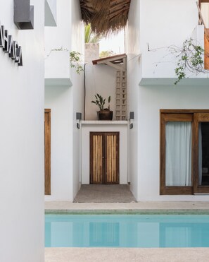 A poolside area with a concrete deck, a wooden door, and a potted plant. - PALAPA HAMACA casita with Pool and AC in vibrant San Francisco (San Francisco)