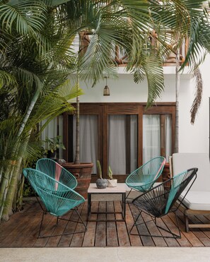 Eine Terrasse mit zwei Stühlen, einem Tisch und einem Blumentopf.