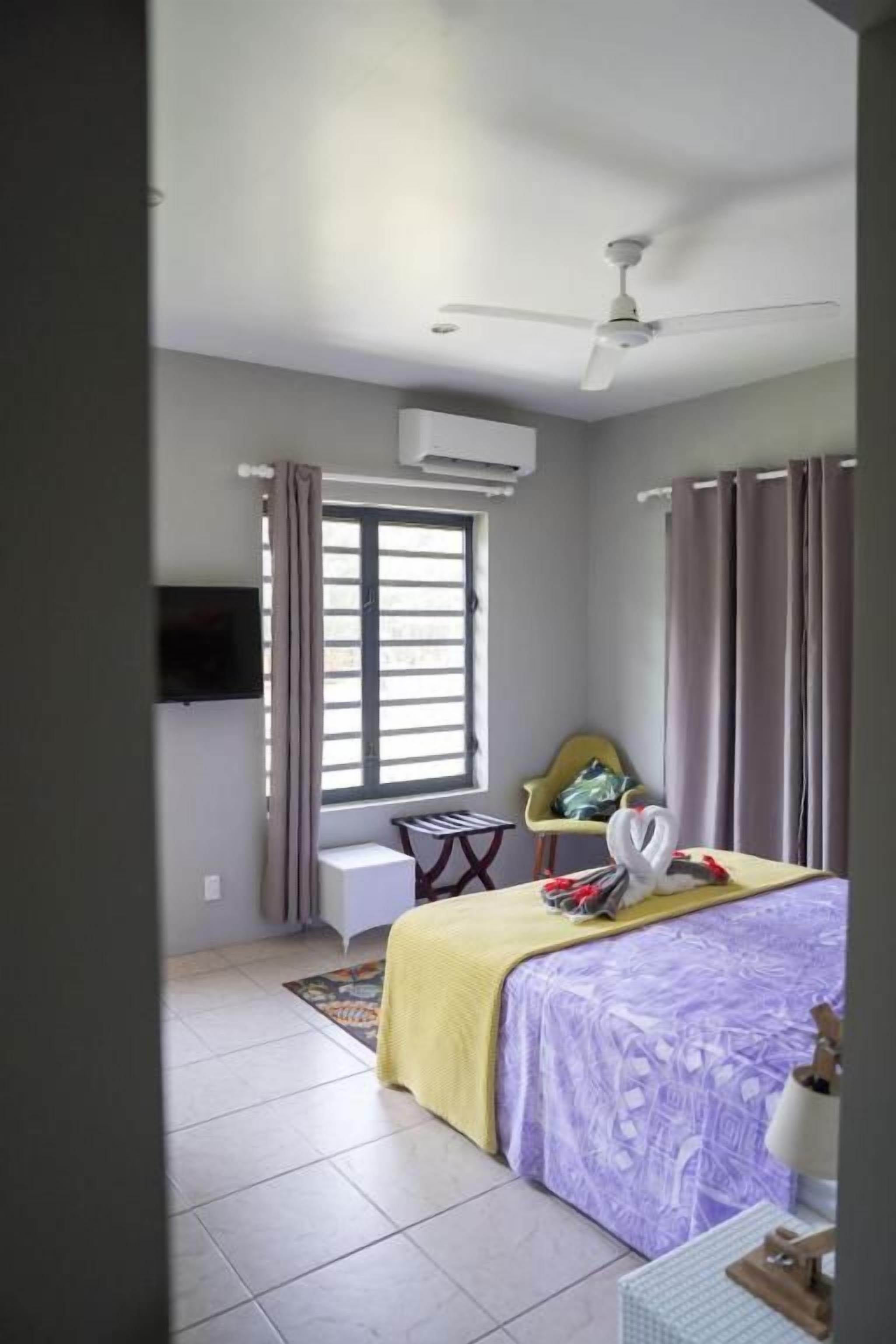 A bedroom with a bed, a chair, a desk, and a window.