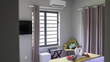 A bedroom with a bed, a chair, a desk, and a window.