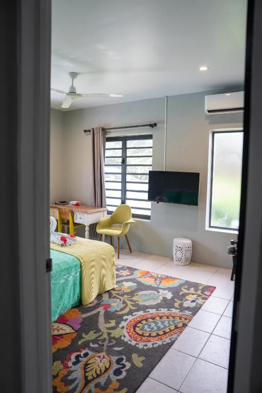 Un dormitorio con cama, escritorio, silla, televisor y ventana.