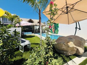 A pool area with artificial grass, lounge chairs, and a large rock. - Pool House 311 by Diana (Jocotepec)
