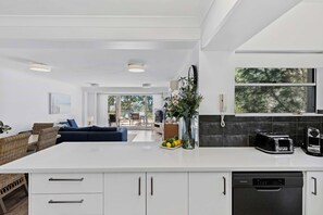 Una cocina moderna con una isla grande, armarios blancos y un lavavajillas integrado.