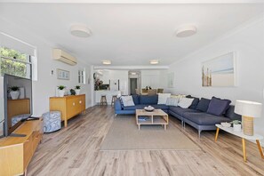 Una sala de estar moderna con un sofá, una mesa de centro y un comedor al fondo.