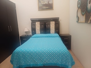 A bedroom with a bed, a nightstand, a lamp, a wardrobe, and a painting on the wall. - Vrbo Property (Toluca de Lerdo)