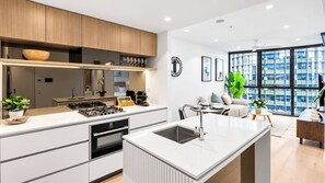 A modern kitchen with a central island, built-in appliances, and a dining area with a view of the city. - Queen’s Wharf 1BR + Free Parking | Brisbane CBD (Brisbane)