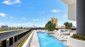 A rooftop swimming pool with a city view, surrounded by modern outdoor seating and planters. - Queen’s Wharf 1BR + Free Parking | Brisbane CBD (Brisbane)