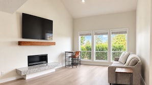 Una sala de estar moderna con una televisión de pantalla plana, una chimenea, un sofá y un comedor con una mesa y sillas.