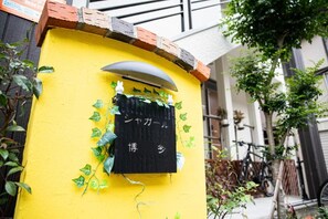 Eine gelbe Wand mit einem schwarzen Schild, das japanische Schriftzeichen zeigt.
