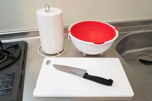 A kitchen counter with a white cutting board, a knife, a roll of paper towels, and a red and white colander. - Chagall Hakata (Fukuoka City Hakata-ku Katakasu)