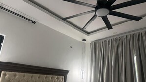 Una stanza con ventilatore a soffitto, una testiera e una finestra con tende.