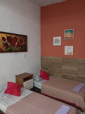 Un dormitorio con dos camas individuales, una mesita de noche, un cabecero de madera y un cuadro de flores rojas en la pared.