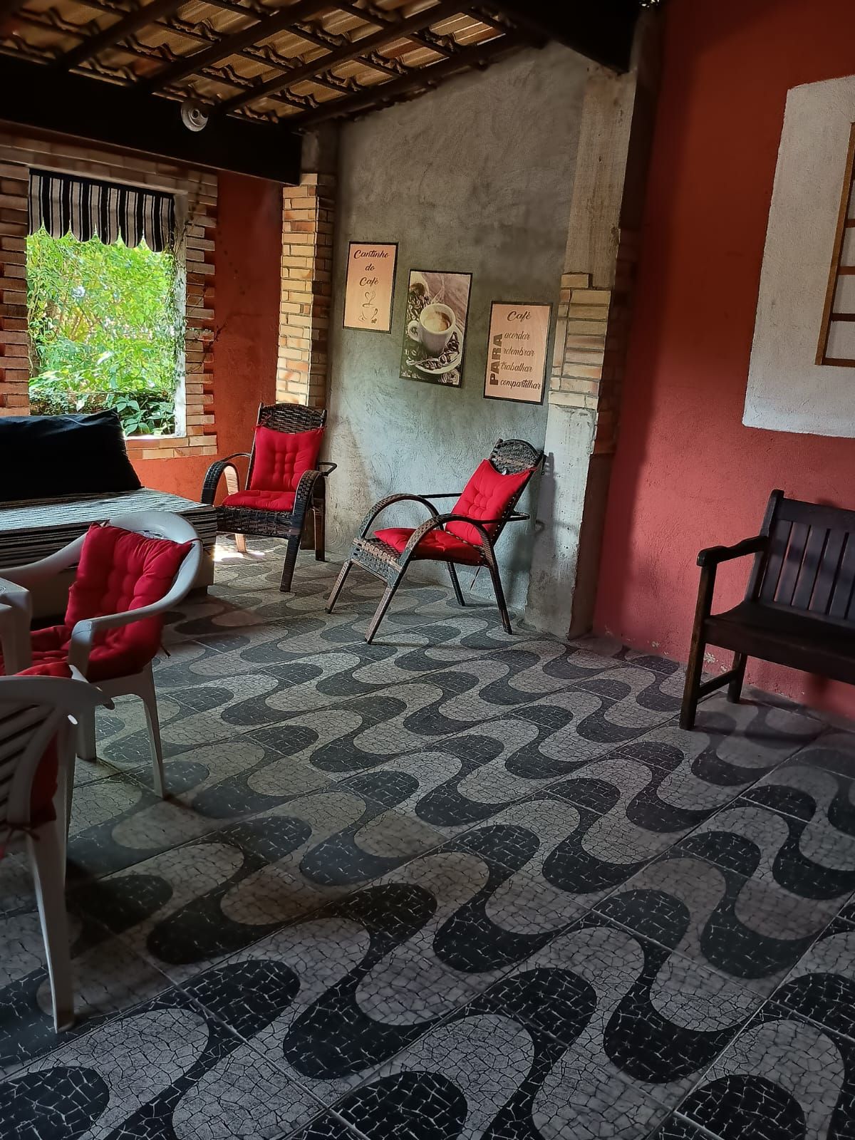 Un café acogedor con sillas de mimbre, piso estampado y pared de ladrillo.