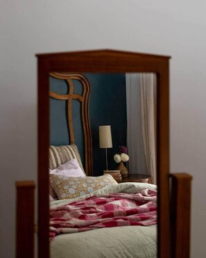 A bedroom with a wooden headboard, a bedside table with a lamp, and a bed with patterned bedding. - Secret Garden Stay – Minusha (Forestville)