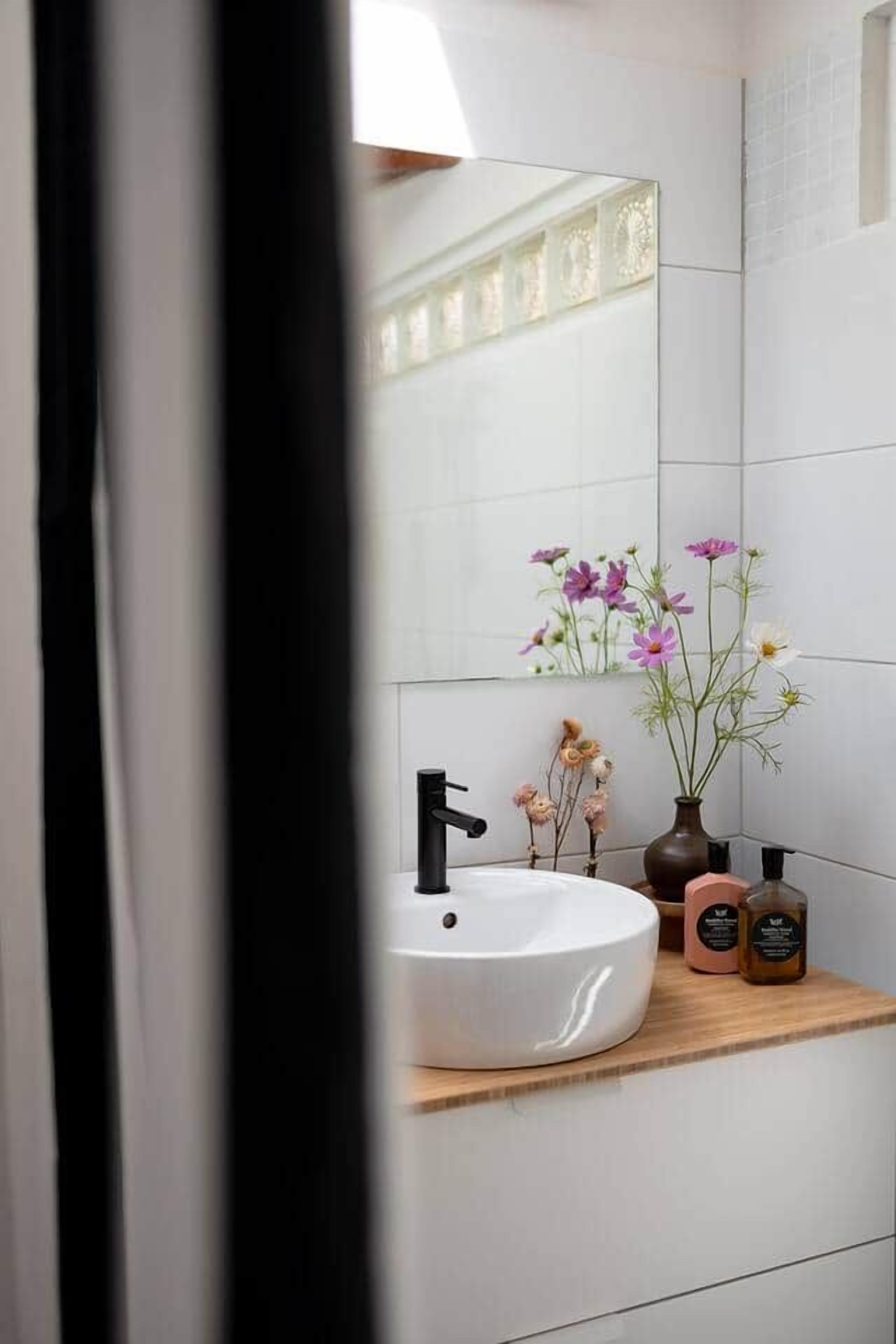 A bathroom with a white sink, a mirror, and a wooden countertop.