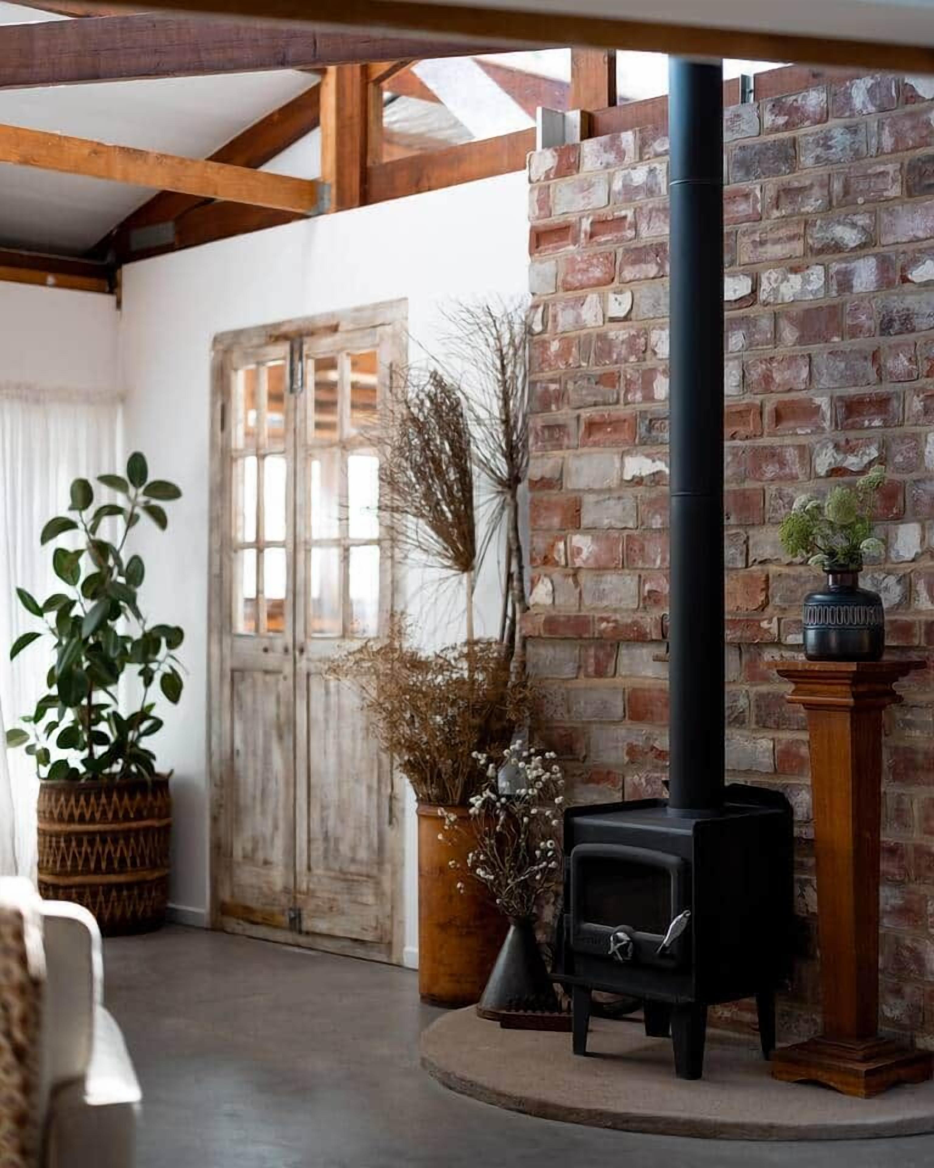 A rustic interior with a brick wall, a wooden door, and a black stove.