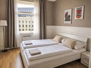 Ein Hotelzimmer mit zwei Betten, einem Heizkörper, einer Lampe und einem Fenster mit Vorhängen.