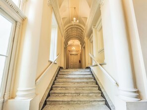 Eine prächtige Treppe mit Marmorstufen und weißen Säulen, die zu einer Tür am Ende führt.