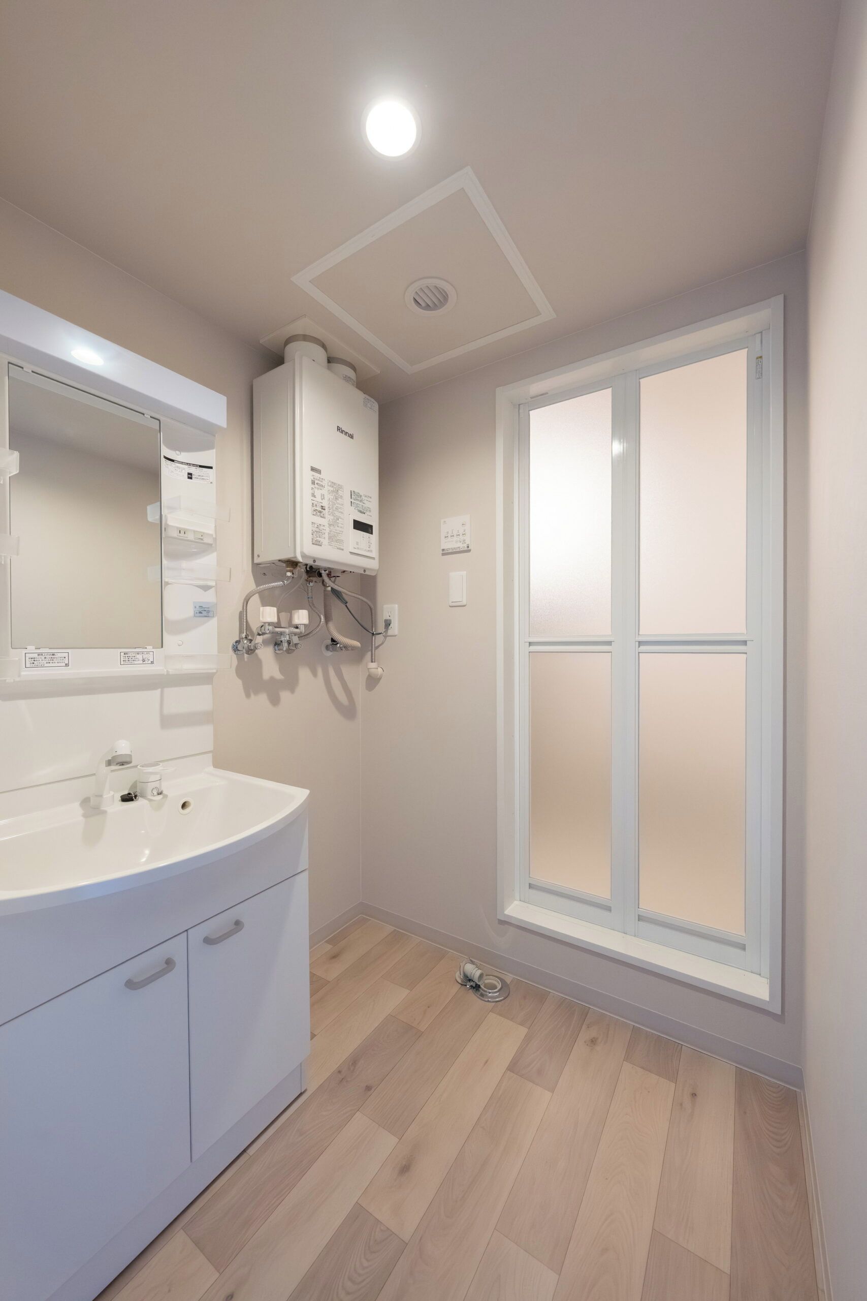 A modern bathroom with a white sink, mirror, and a large window.
