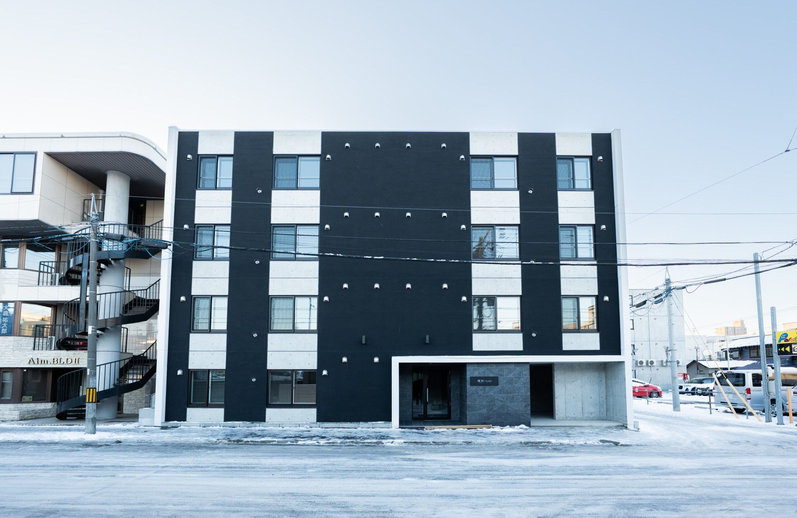 A modern building with a black and white facade, multiple windows, and a visible entrance.