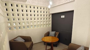 Una habitación con dos sofás, una mesita redonda y un techo perforado.