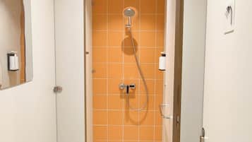 Un baño estrecho con ducha, paredes blancas y azulejos naranjas.
