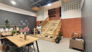 Un interior moderno con una escalera de madera, una zona de comedor con mesa y sillas, y un espacio de estar con una mesa redonda.
