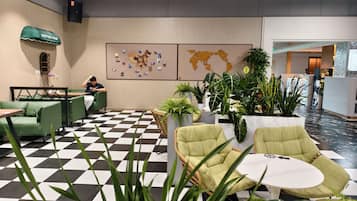 Un vestíbulo con piso a cuadros, zonas de estar y una pared con un mapa del mundo.