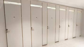 A row of white, wall-mounted cabinets with handles, likely for storage, in a clean, tiled room.