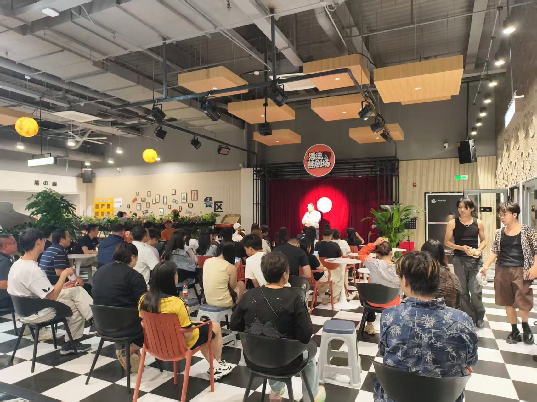 A conference room with a stage, audience seating, and a checkered floor.