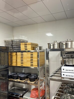 A kitchen with stainless steel appliances, wooden storage shelves, and plastic containers. - Yunfuli Qingcheng Housi (Chengdu)