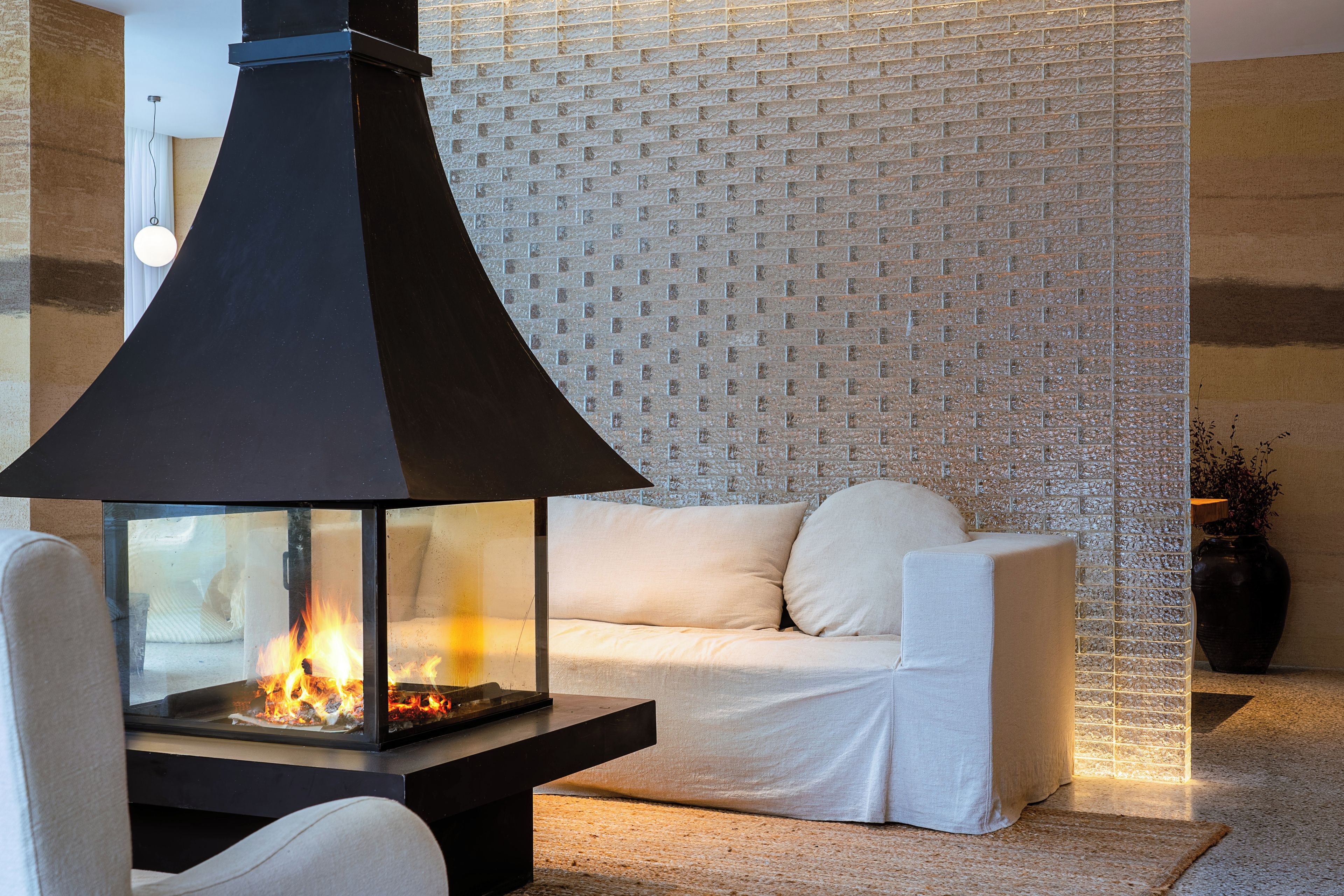 Un interior moderno con chimenea, un sofá blanco y una pared texturizada.