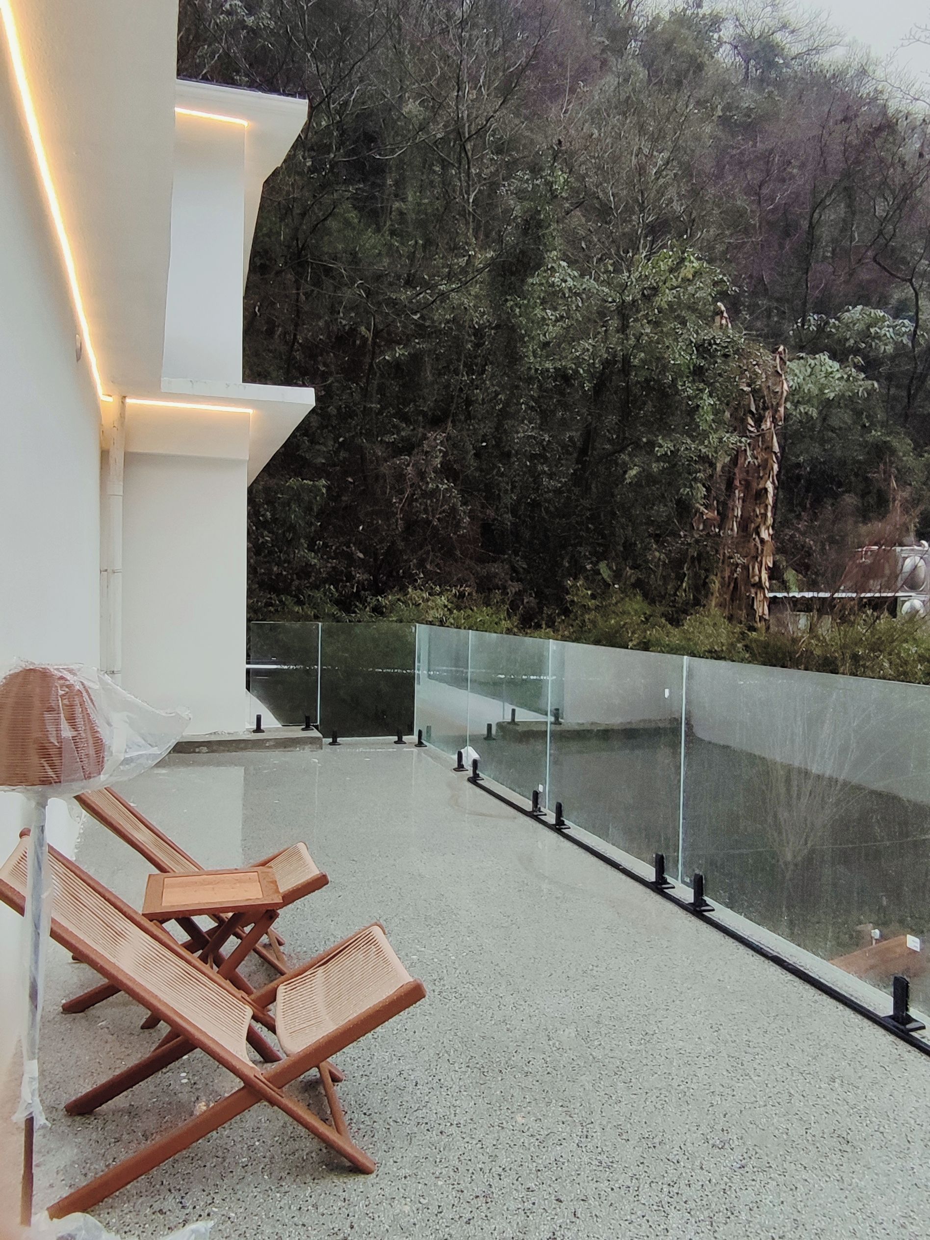 Terraza en la azotea con mobiliario y vistas a una zona boscosa.