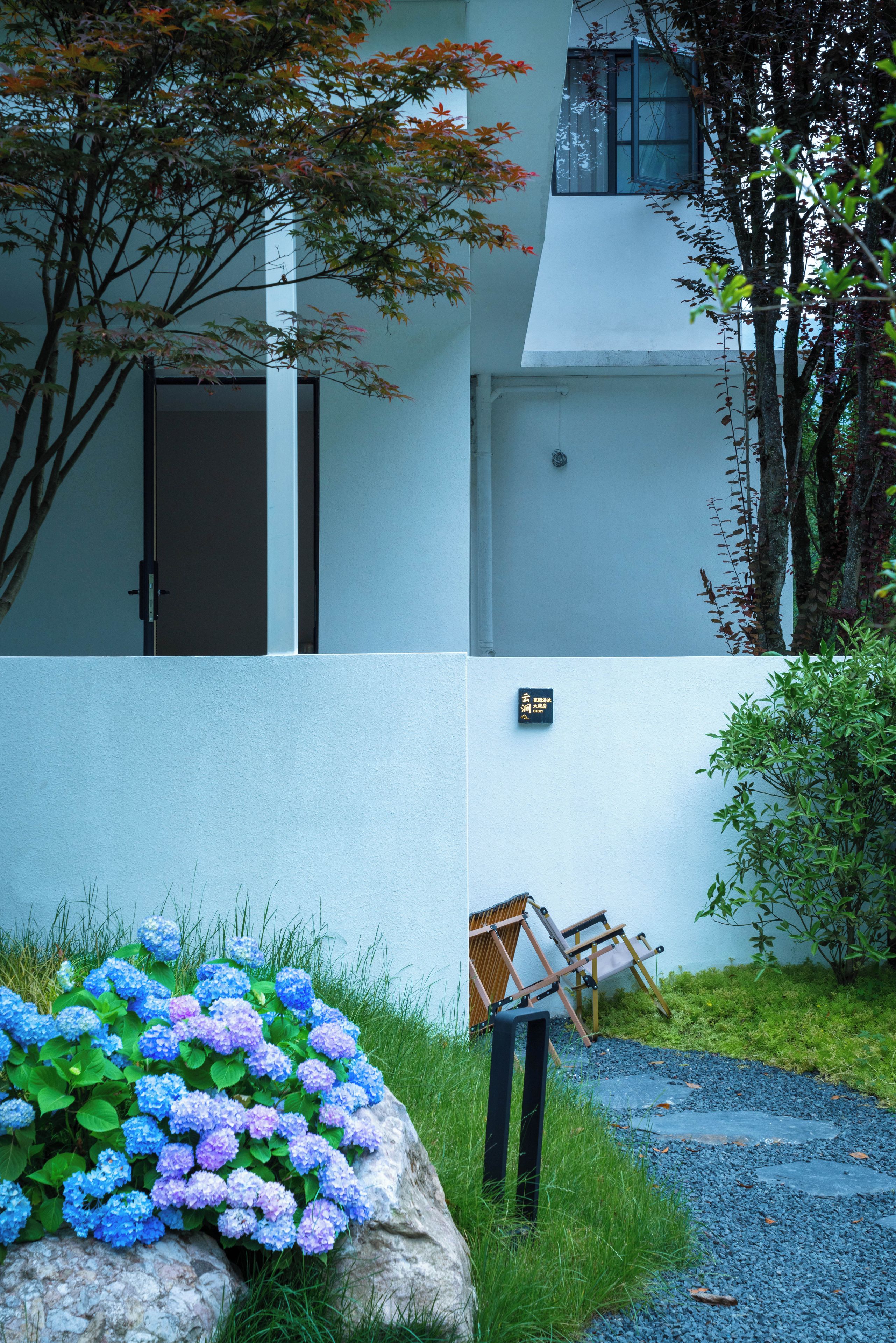 Un edificio con fachada blanca, una puerta y un pequeño letrero en la pared.