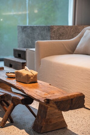 Un banc en bois avec un coussin, un lit avec un oreiller et un mur en pierre dans une chambre d’hôtel.