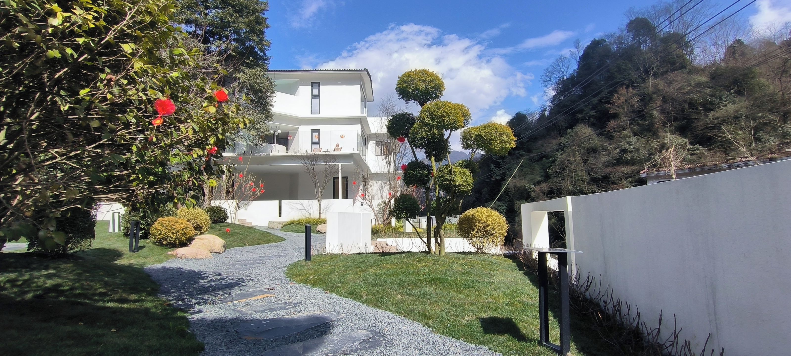 A modern two-story house with a paved driveway leading to the entrance.