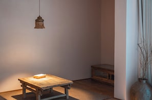 A room with a wooden table, a hanging light fixture, and a vase with branches.