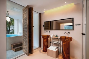 A modern bathroom with a glass shower enclosure, two wooden-framed sinks, and a built-in shelf with toiletries.