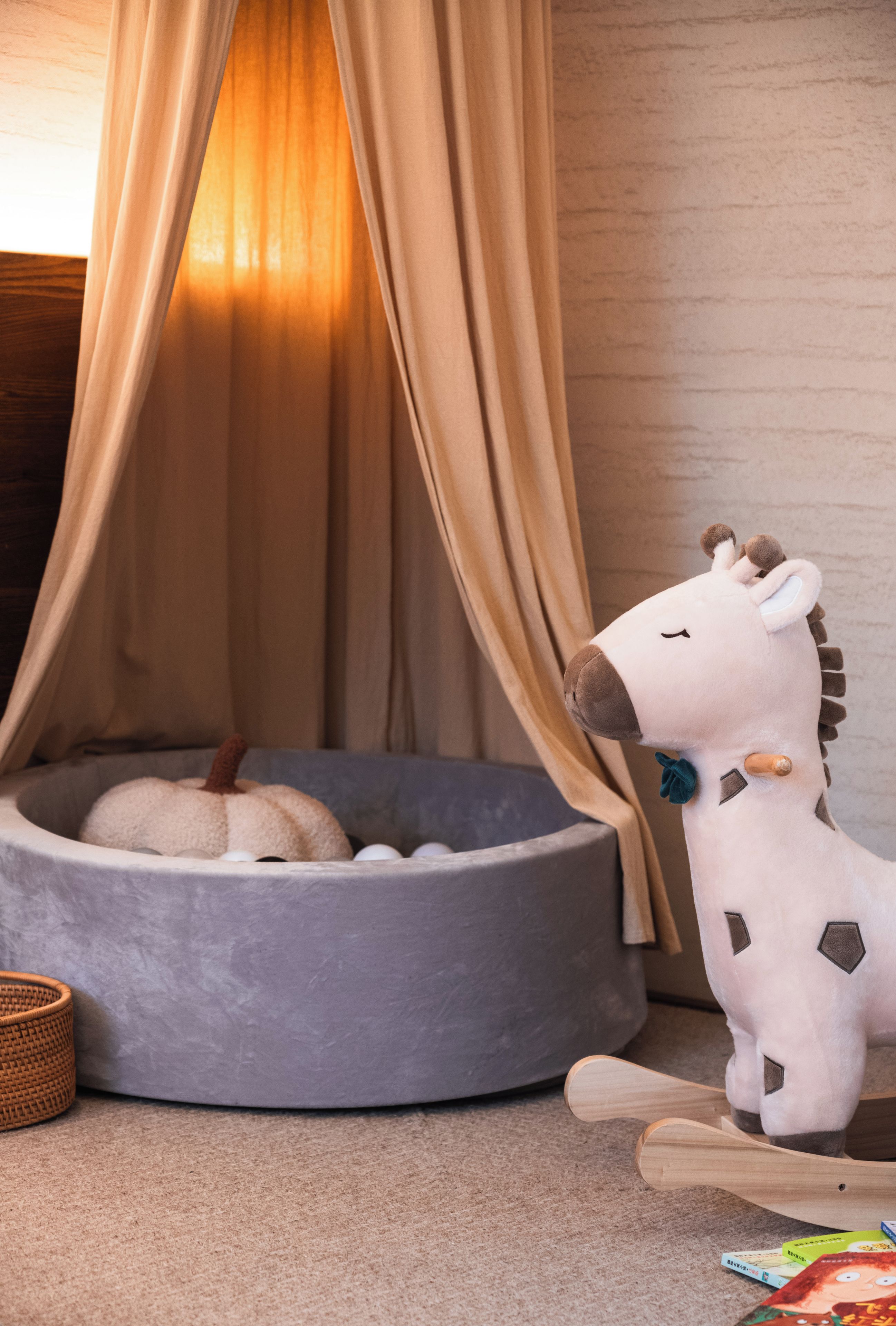 A room with a grey pet bed, a white stuffed toy, and a woven basket.
