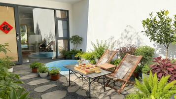 Un patio con piscina, sillas de descanso y una mesa con fruta fresca.