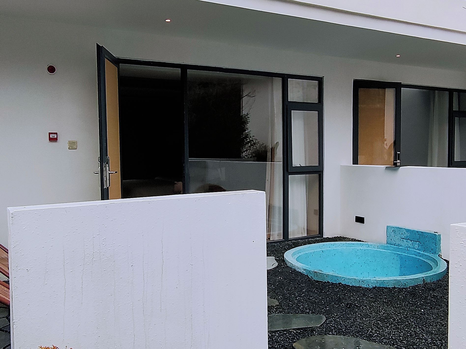 A modern outdoor area with a swimming pool, a sliding glass door, and a white partition.