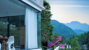 Um edifício moderno com grandes janelas, uma escadaria e vista para uma paisagem montanhosa.
