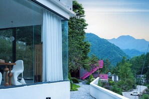 A modern building with large windows, a staircase, and a view of a mountainous landscape. - Yunfuli Qingcheng Housi (Chengdu)