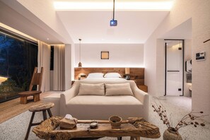 A modern bedroom with a large bed, bedside tables, a wooden headboard, a nightstand, a small table with a bowl and a candle, and a view of the outdoors through a window. - Yunfuli Qingcheng Housi (Chengdu)