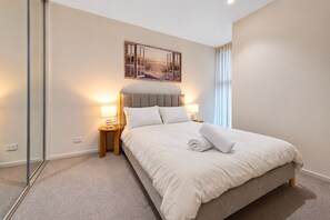 A hotel room with a large bed, two bedside lamps, a painting above the bed, and a window with curtains. - Spacious 3-Bed Townhouse In Mile End (Mile End)
