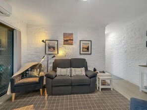 Ein modernes Wohnzimmer mit einer Couch, einem Sessel und zwei gerahmten Bildern an der Wand.