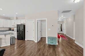Eine moderne Küche mit weißen Schränken, einem schwarzen Kühlschrank und einer Edelstahl-Mülltonne.