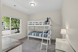 Habitación con literas, una ventana, un escritorio y una lámpara.